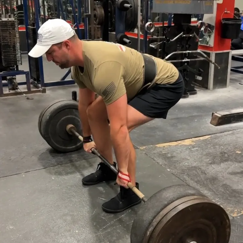 Athlete preparing for heavy deadlift with loaded barbell in commercial gym