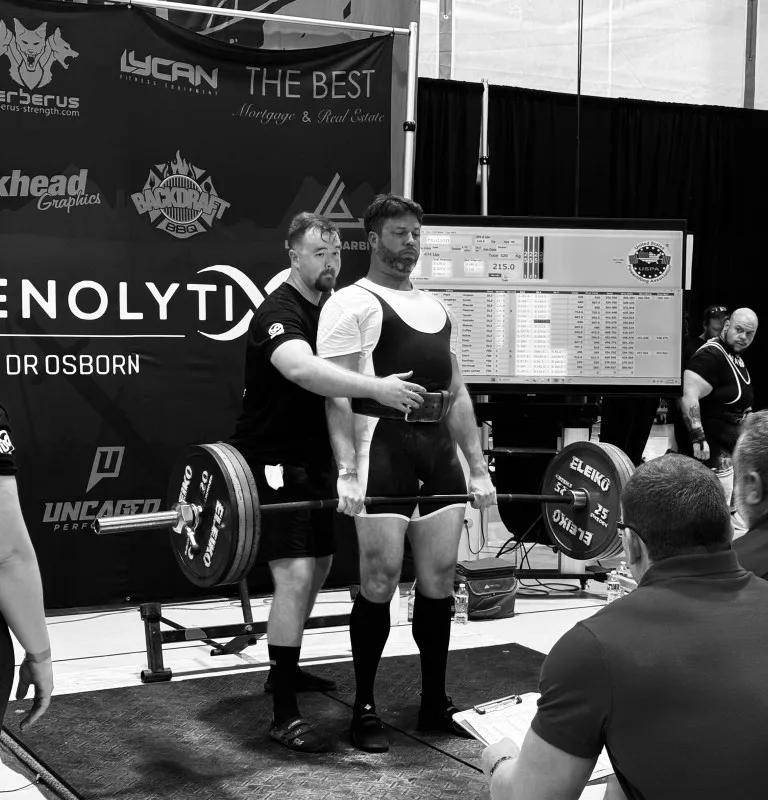 Athlete stepping onto lifting platform toward barbell